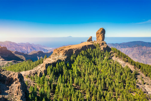 Roque Nublo op Gran Canaria met de opvallende rotsformatie boven op de berg, omringd door ruig vulkanisch landschap en bergtoppen.